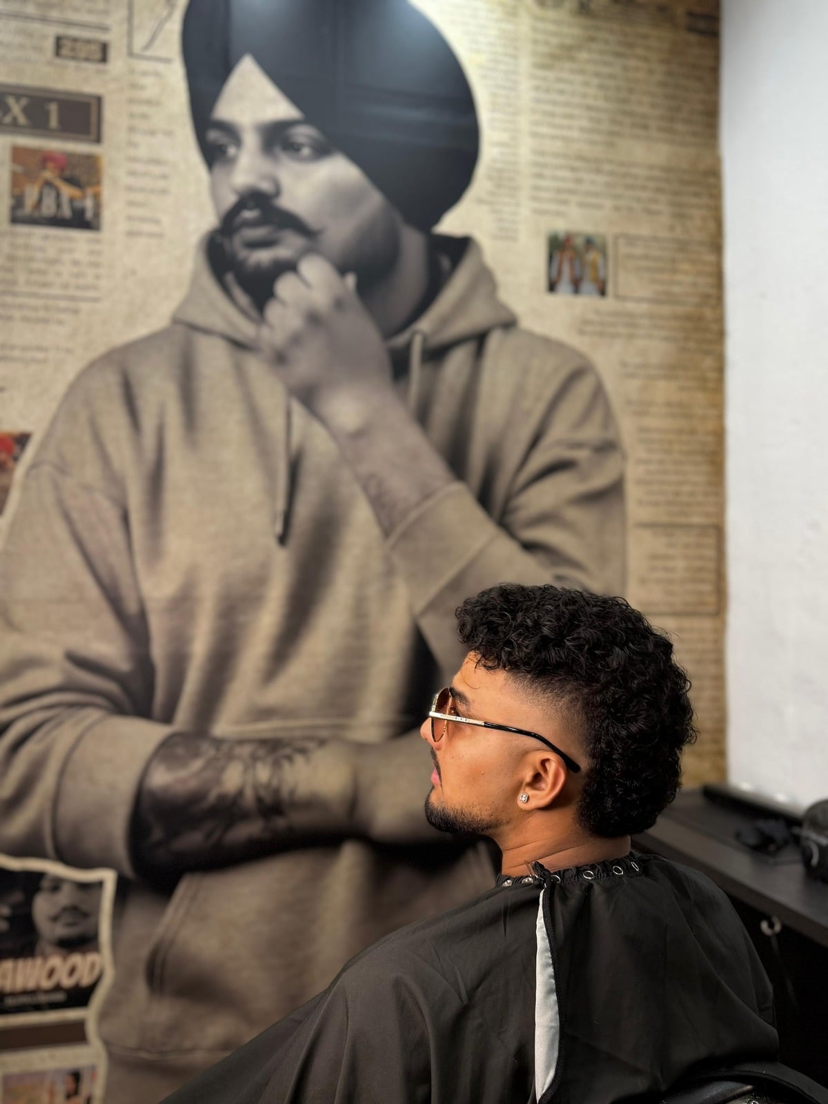 A client facing the newspaper-wall mural inside the PBX1 shop