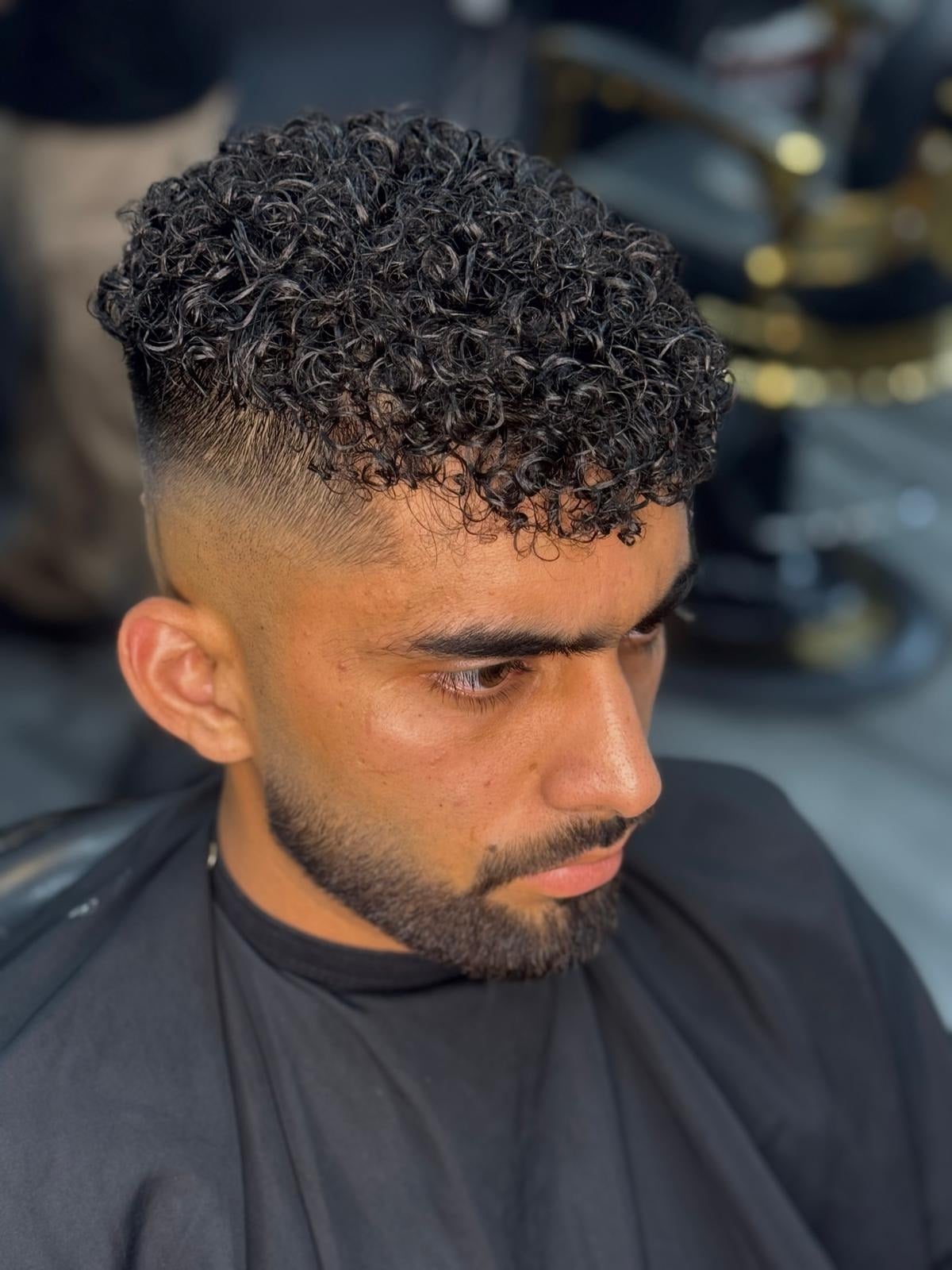 Top down view of a curly perm with a low taper fade and full beard