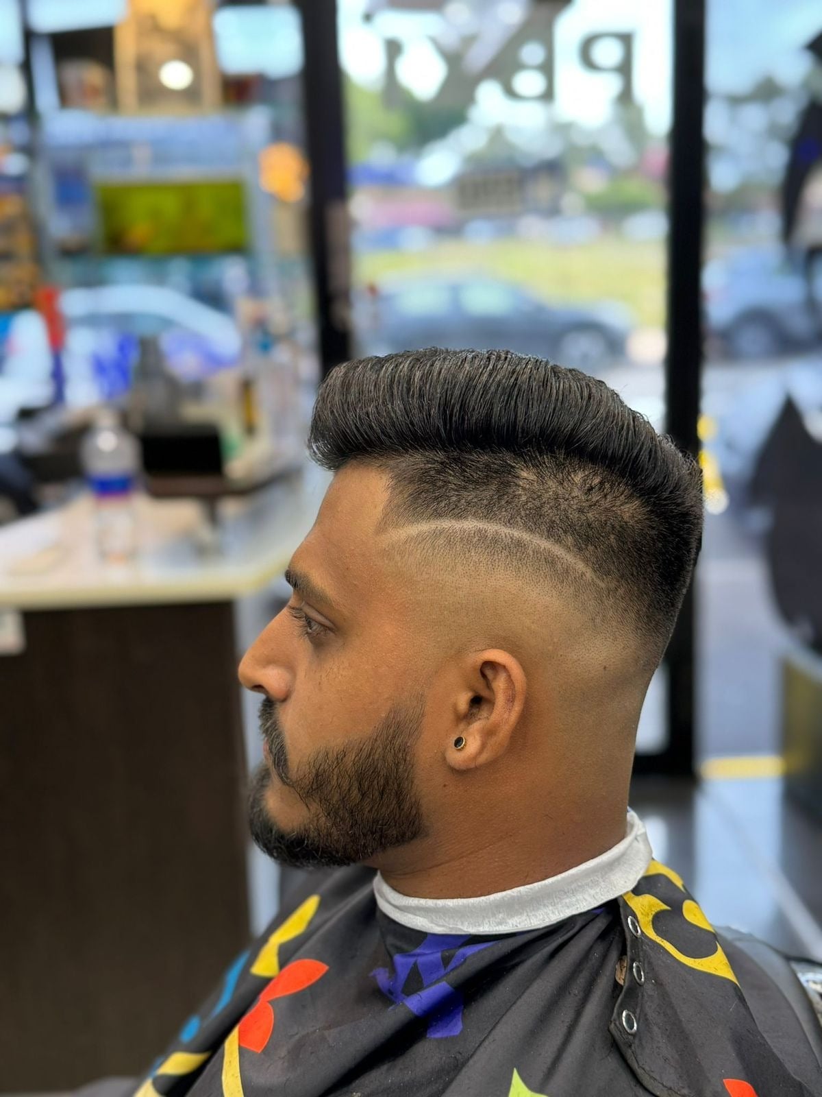 Side profile of a large pompadour with line design and beard