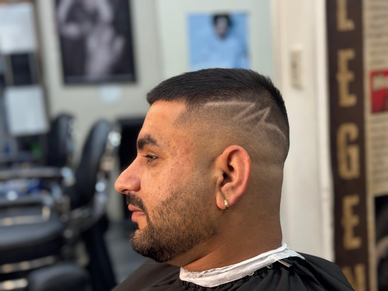 Side profile crop with a hair tattoo line and skin fade beneath the LEGEND wall sign